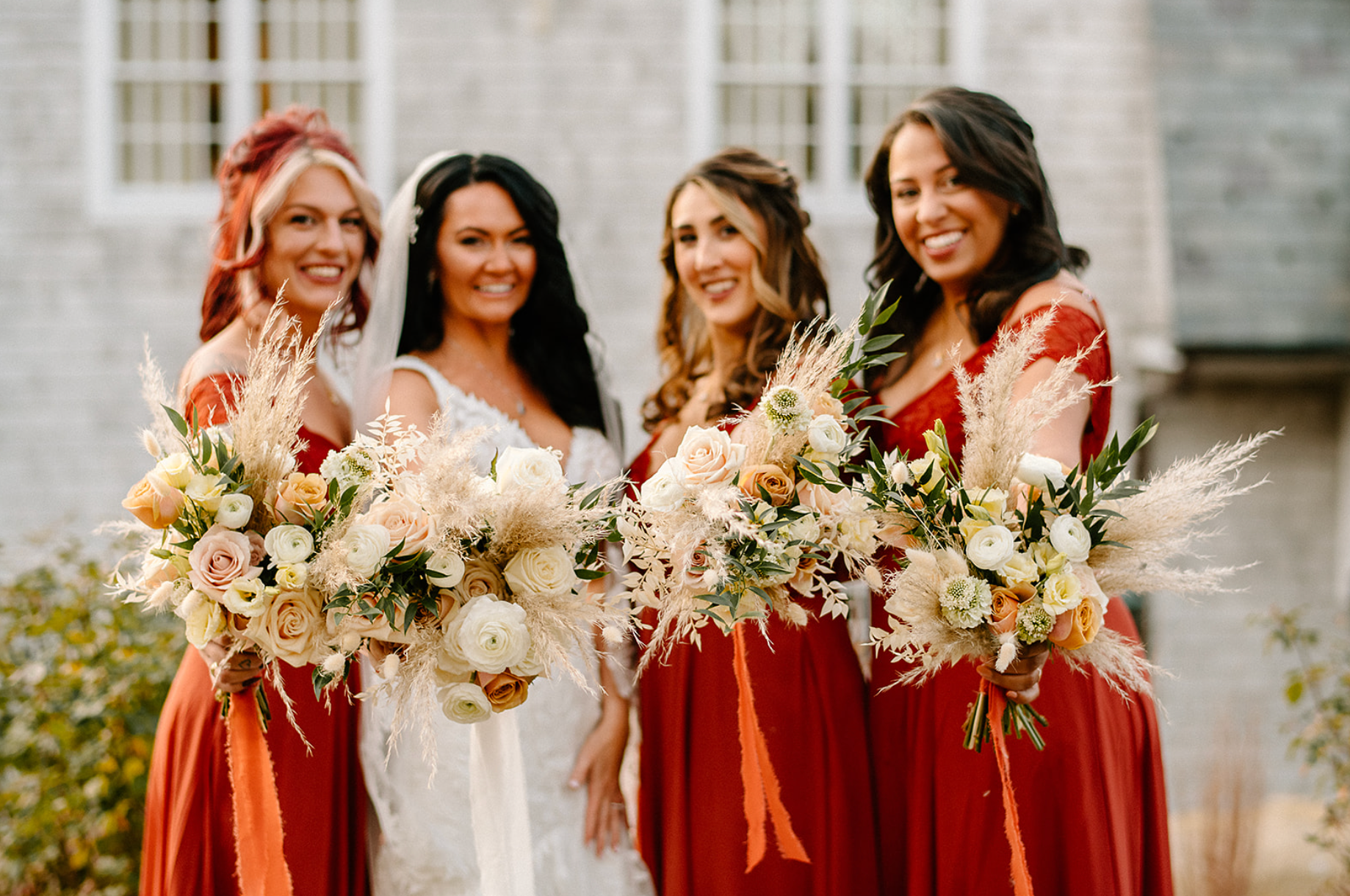 A bride and her bridesmaids are posing for a picture while holding bouquets of flowers.