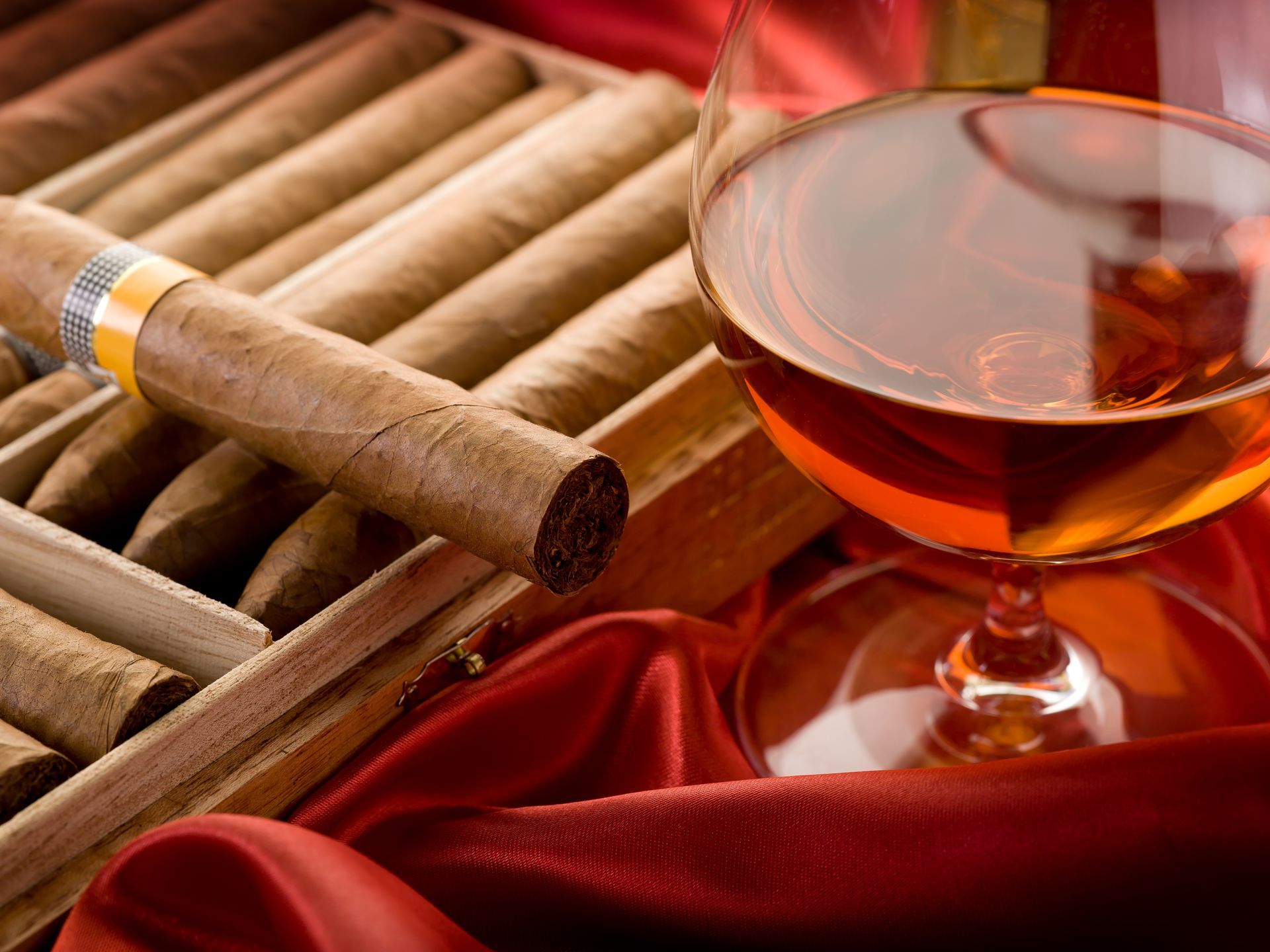 A box of cigars next to a glass of cognac