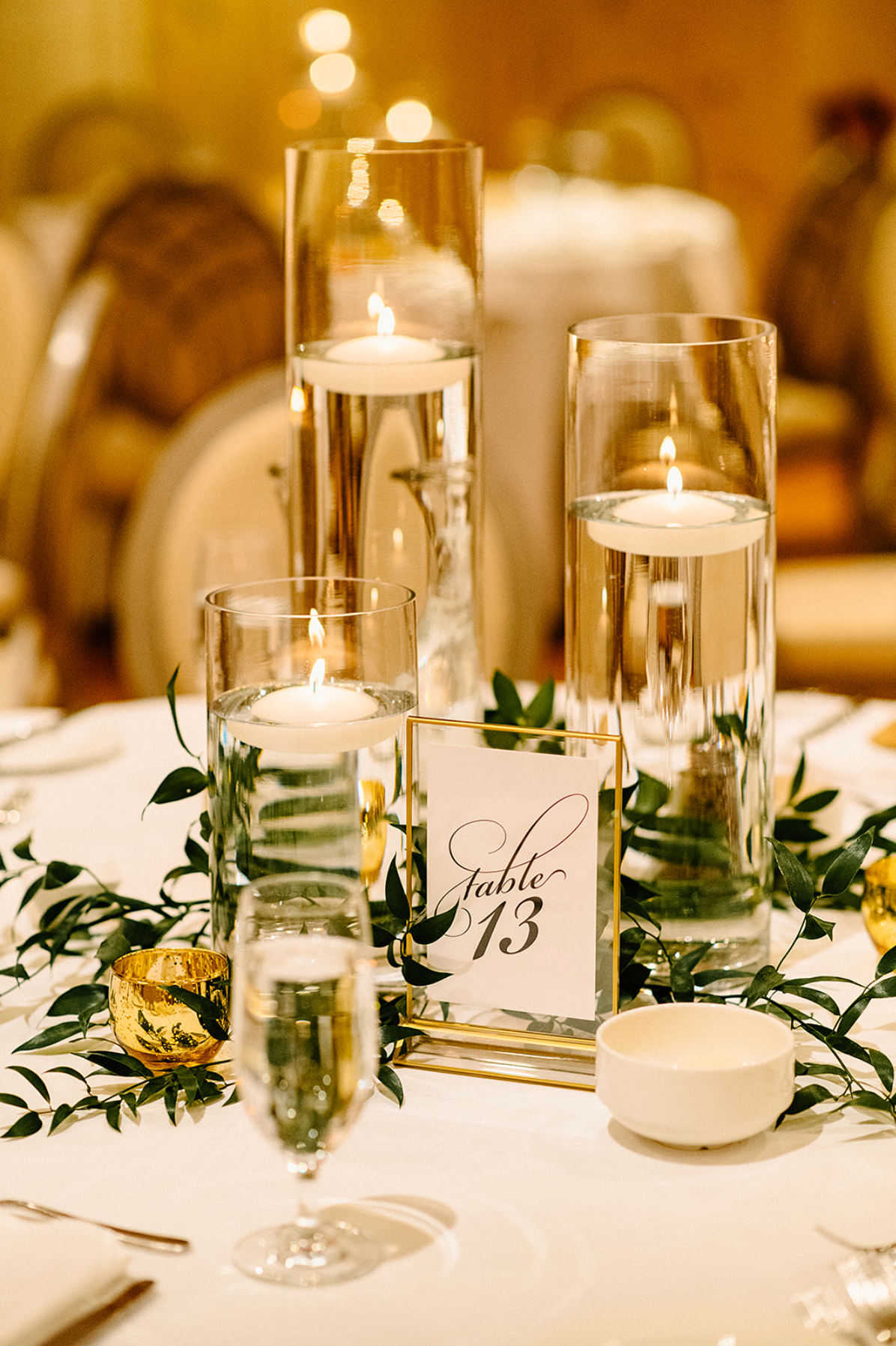 A table with a vase of water and candles on it.