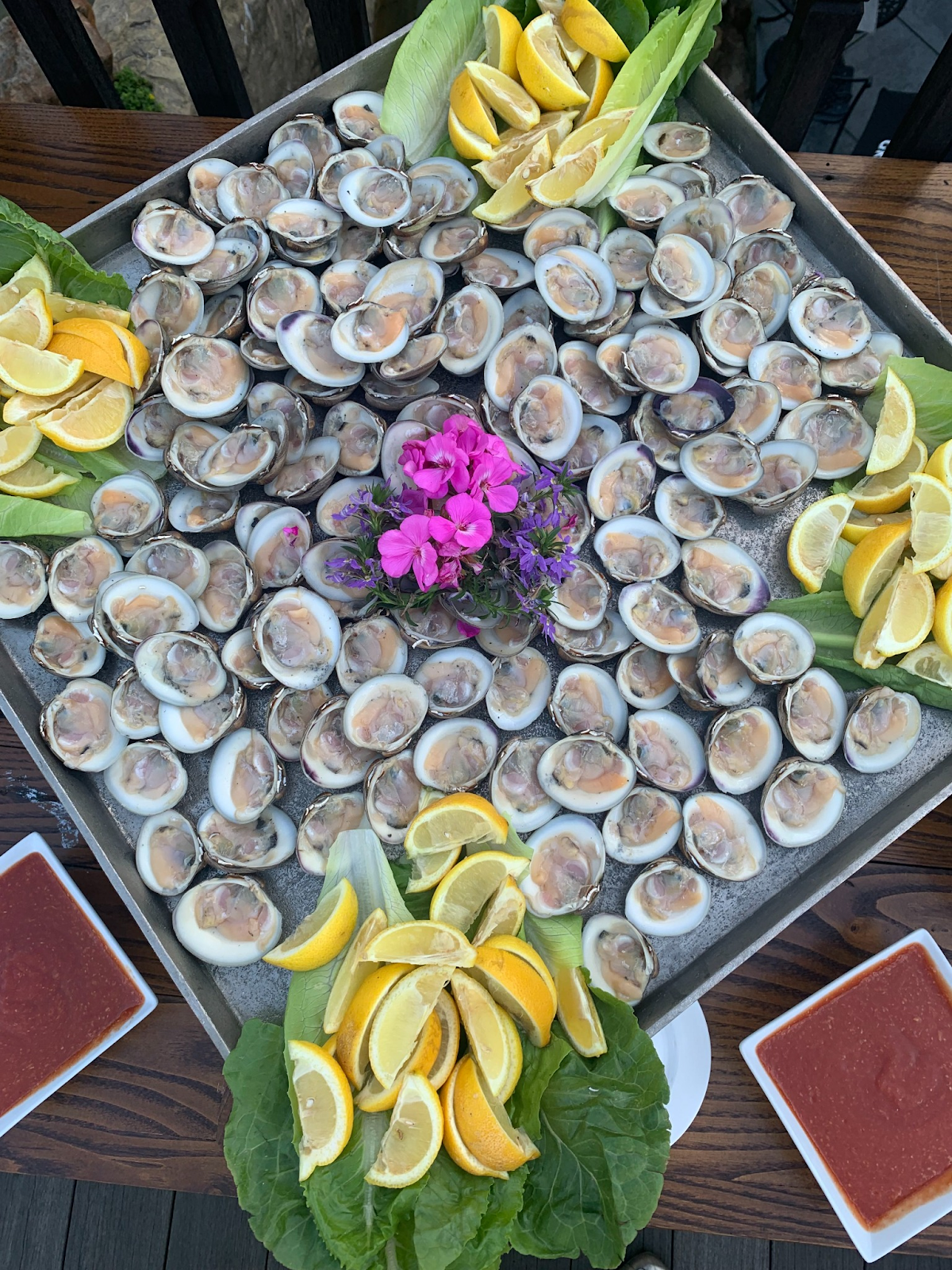 A tray of oysters with lemons and lettuce on a table.