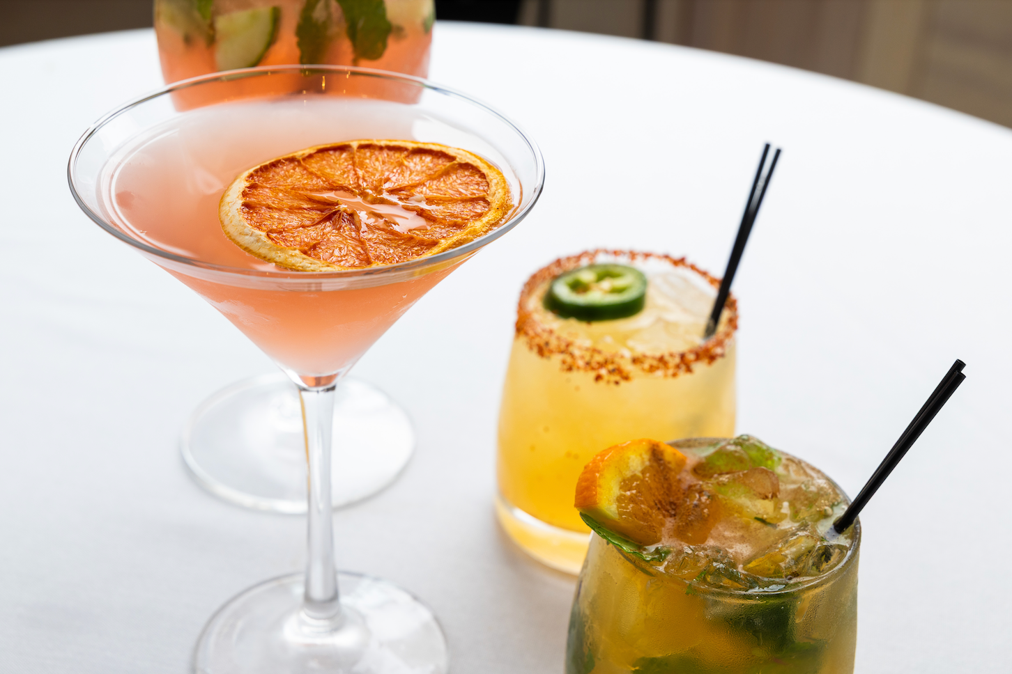 Three different types of cocktails are sitting on a white table.