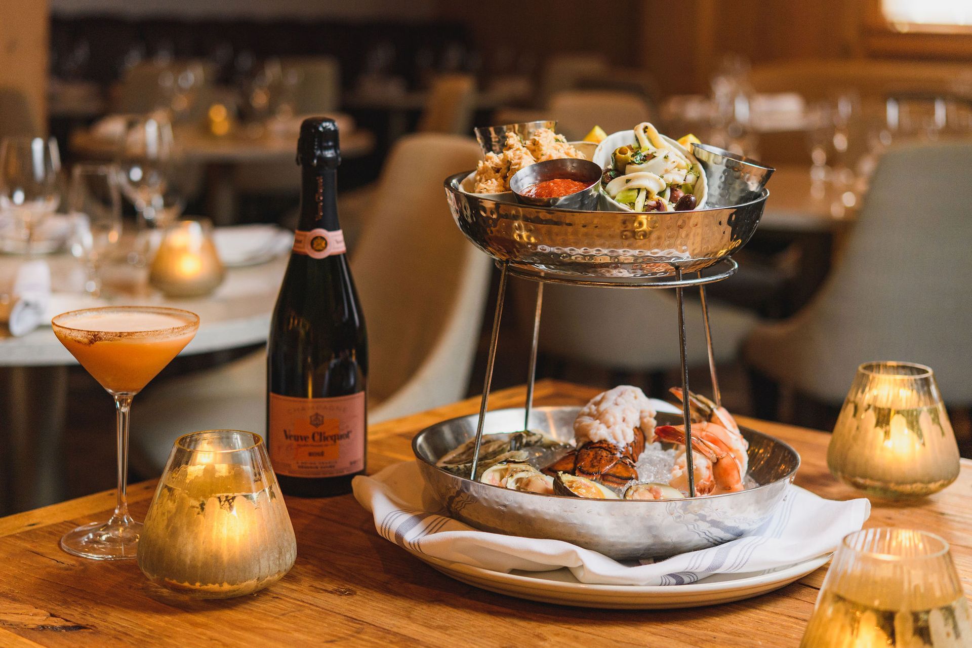 A bottle of champagne and a plate of food are on a table in a restaurant.