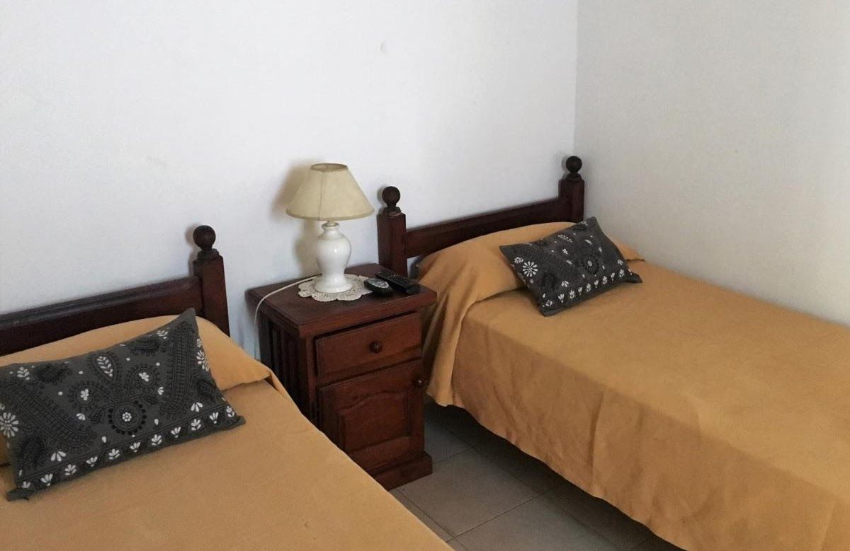 A bedroom with two beds a nightstand and a lamp