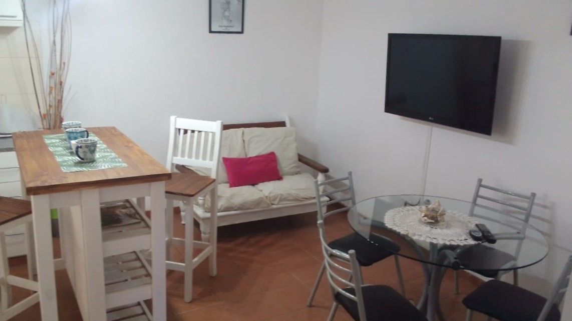 A living room with a table , chairs and a flat screen tv.