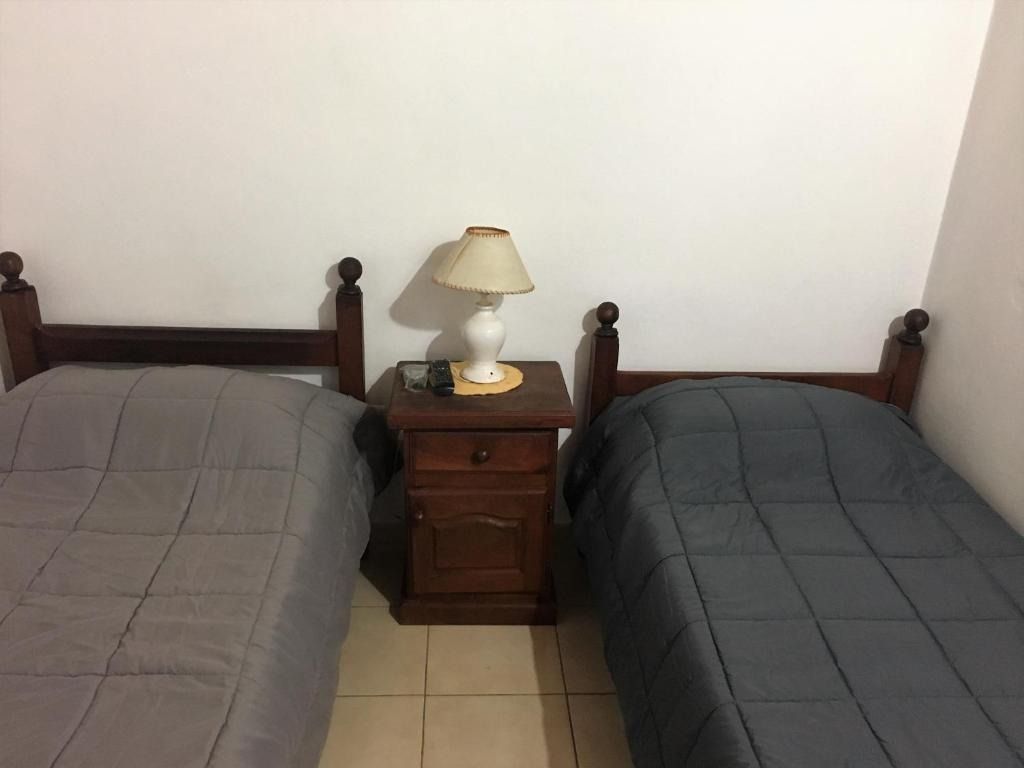 A bedroom with two beds , a nightstand and a lamp.