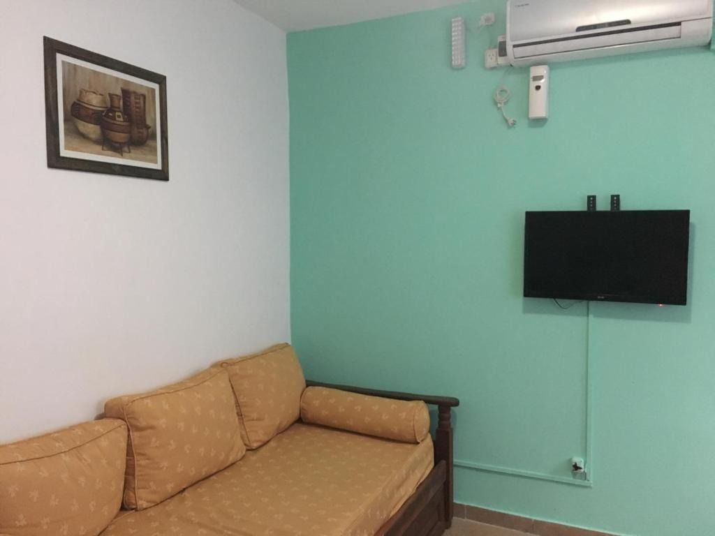 A living room with a couch , television and air conditioner.