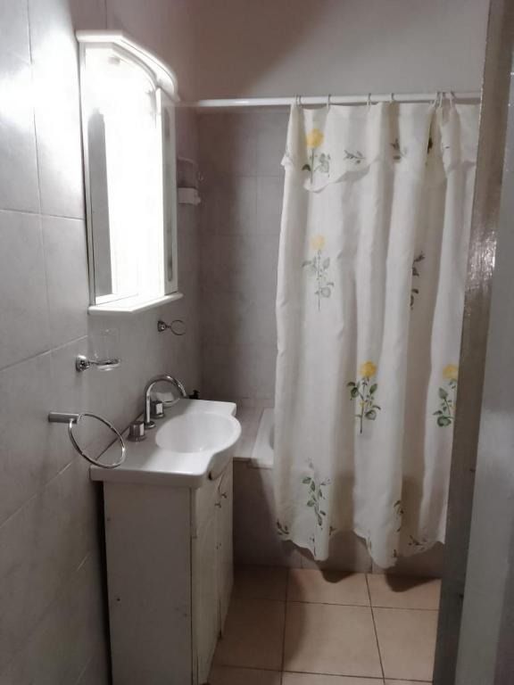 A bathroom with a sink , shower curtain and mirror.