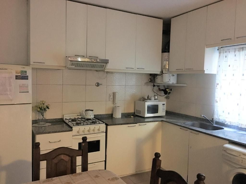 A kitchen with a stove , refrigerator , microwave and sink