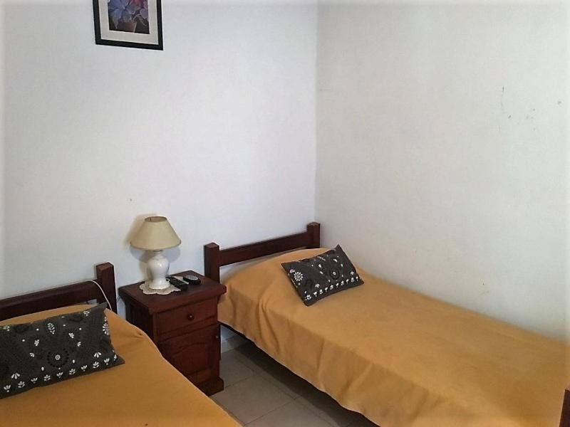 A bedroom with two beds and a lamp on the nightstand