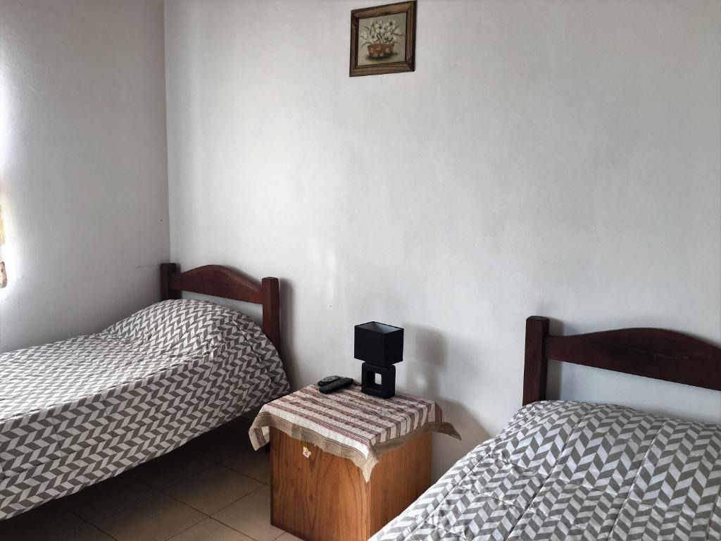 A bedroom with two beds and a nightstand