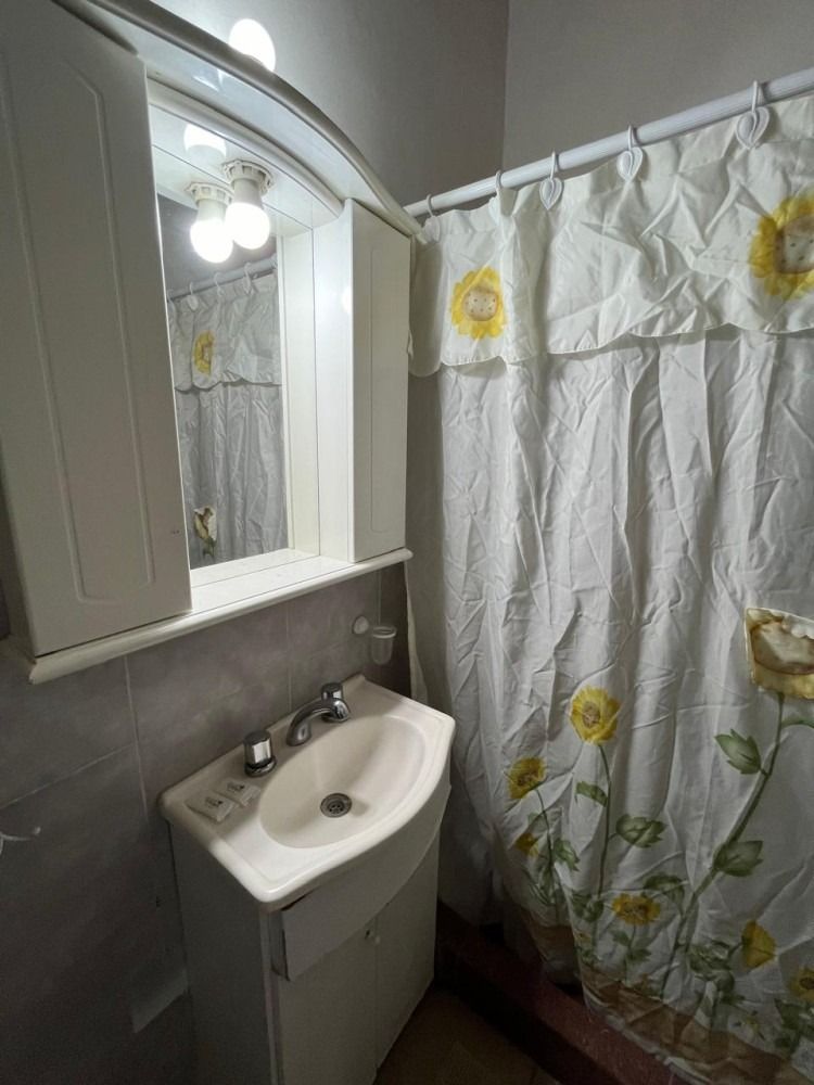 A bathroom with a sink , mirror and shower curtain.