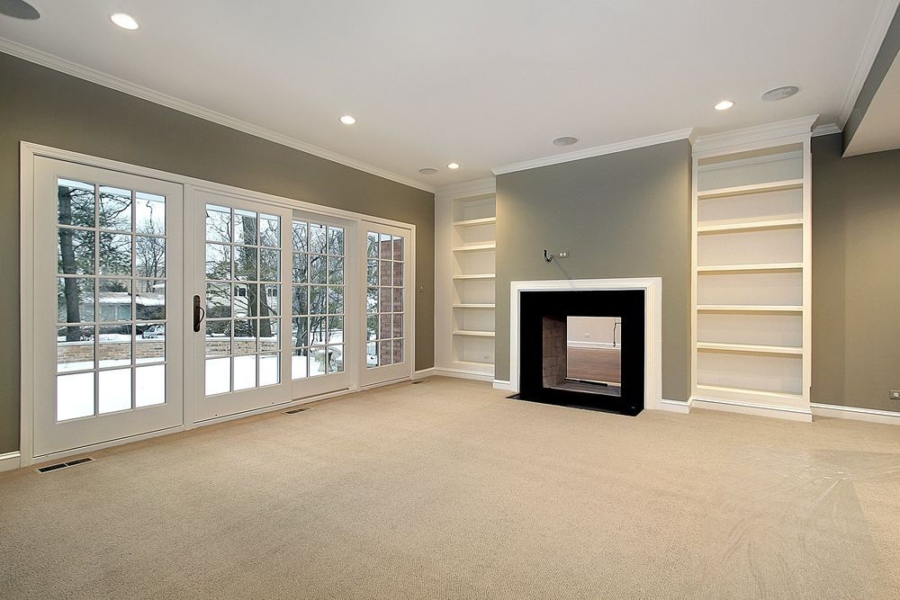 An empty living room with a fireplace and sliding glass doors.