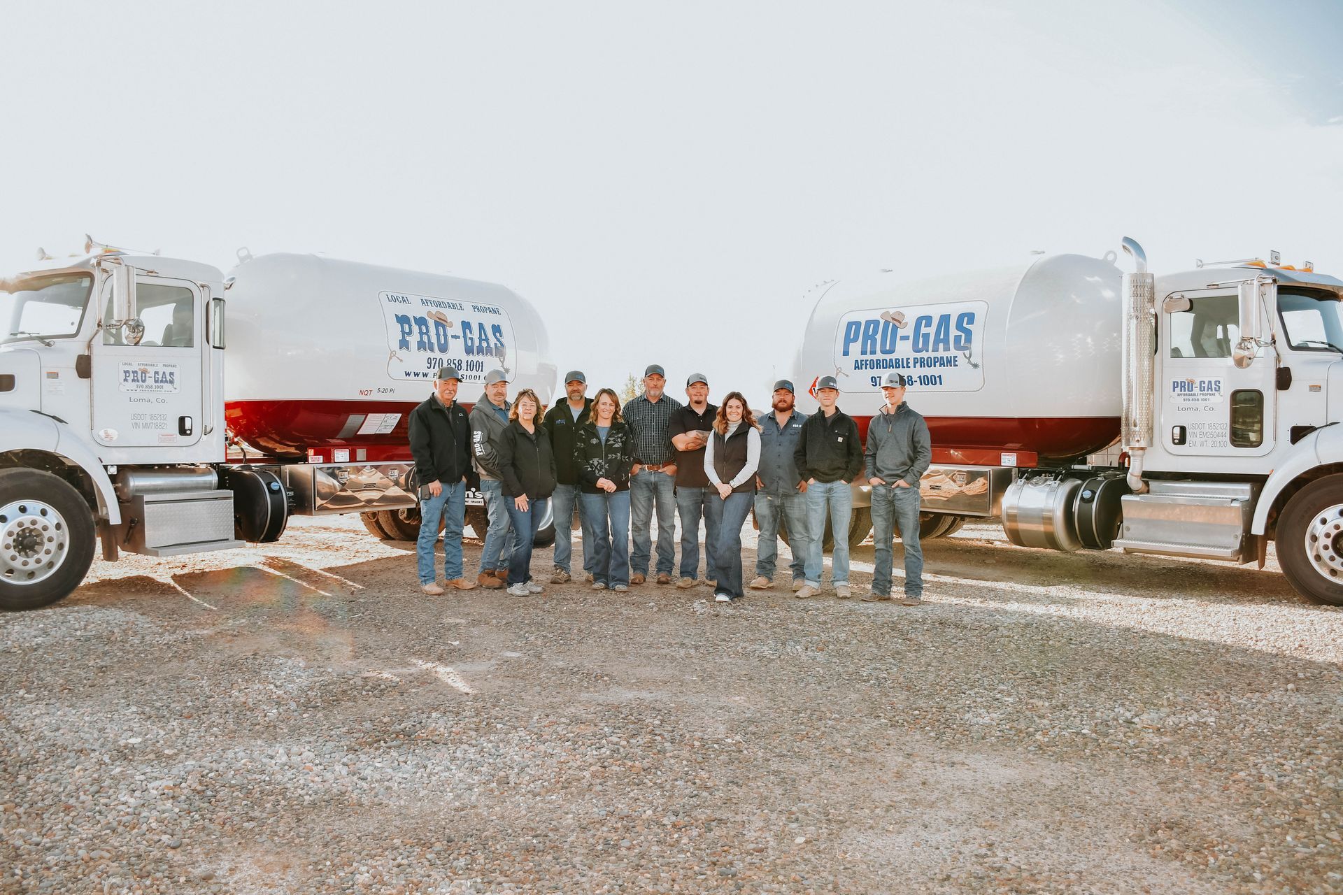White propane tank next to a service truck, with a colorful desert mountain backdrop.