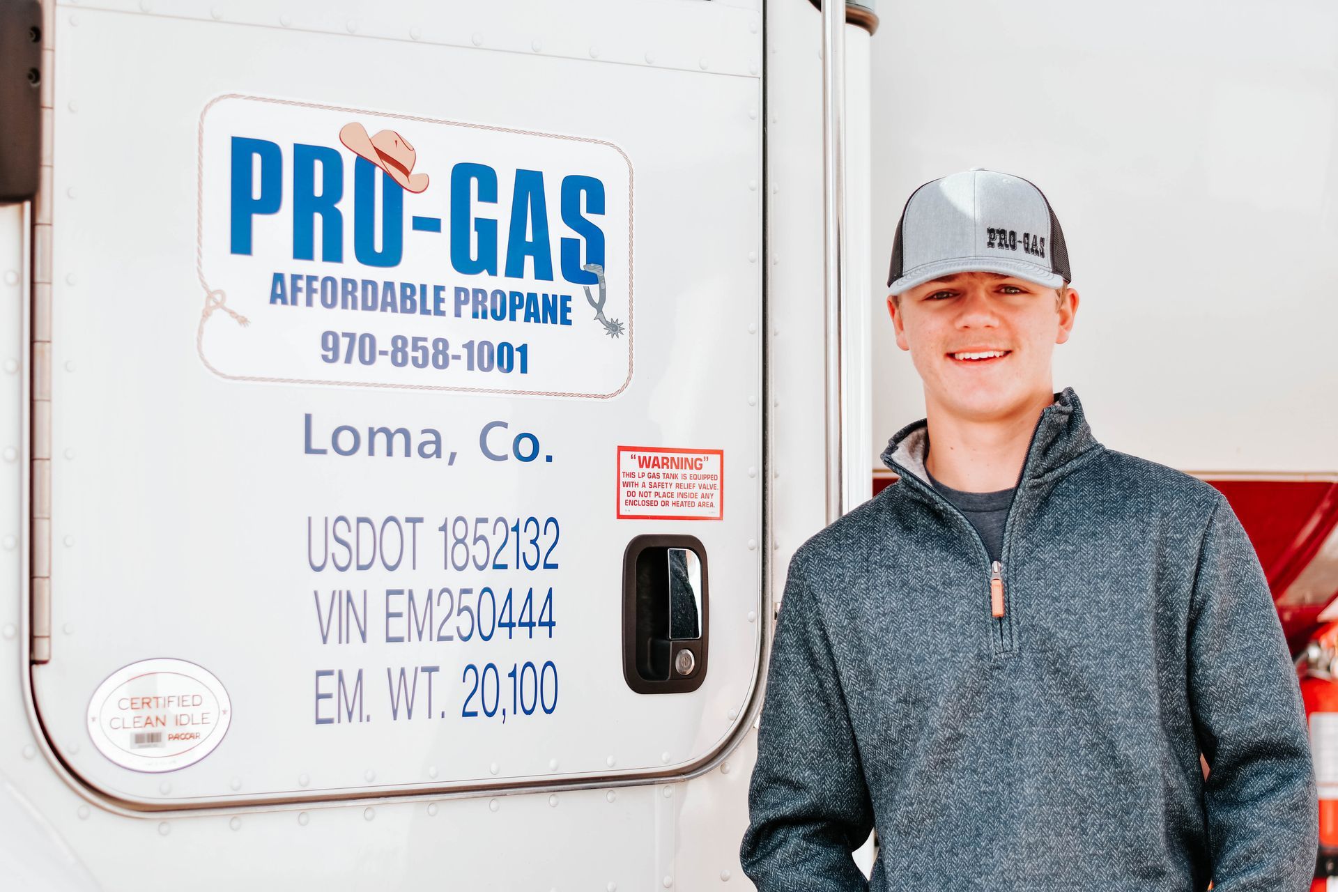 A young person smiles next to a Pro-Gas propane truck in Loma, Colorado.