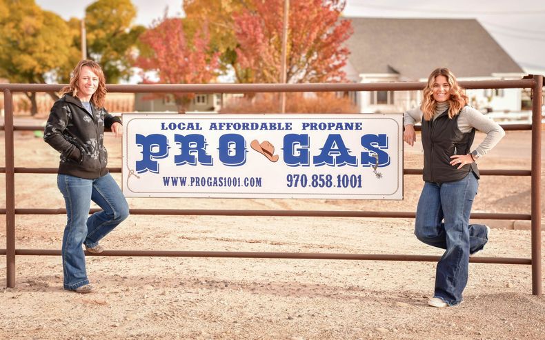 Two women stand by a sign for 