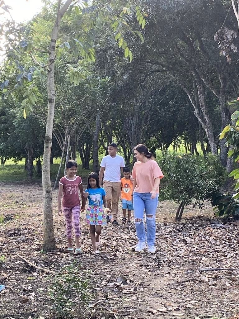 Group of people walking on a path through a wooded area.