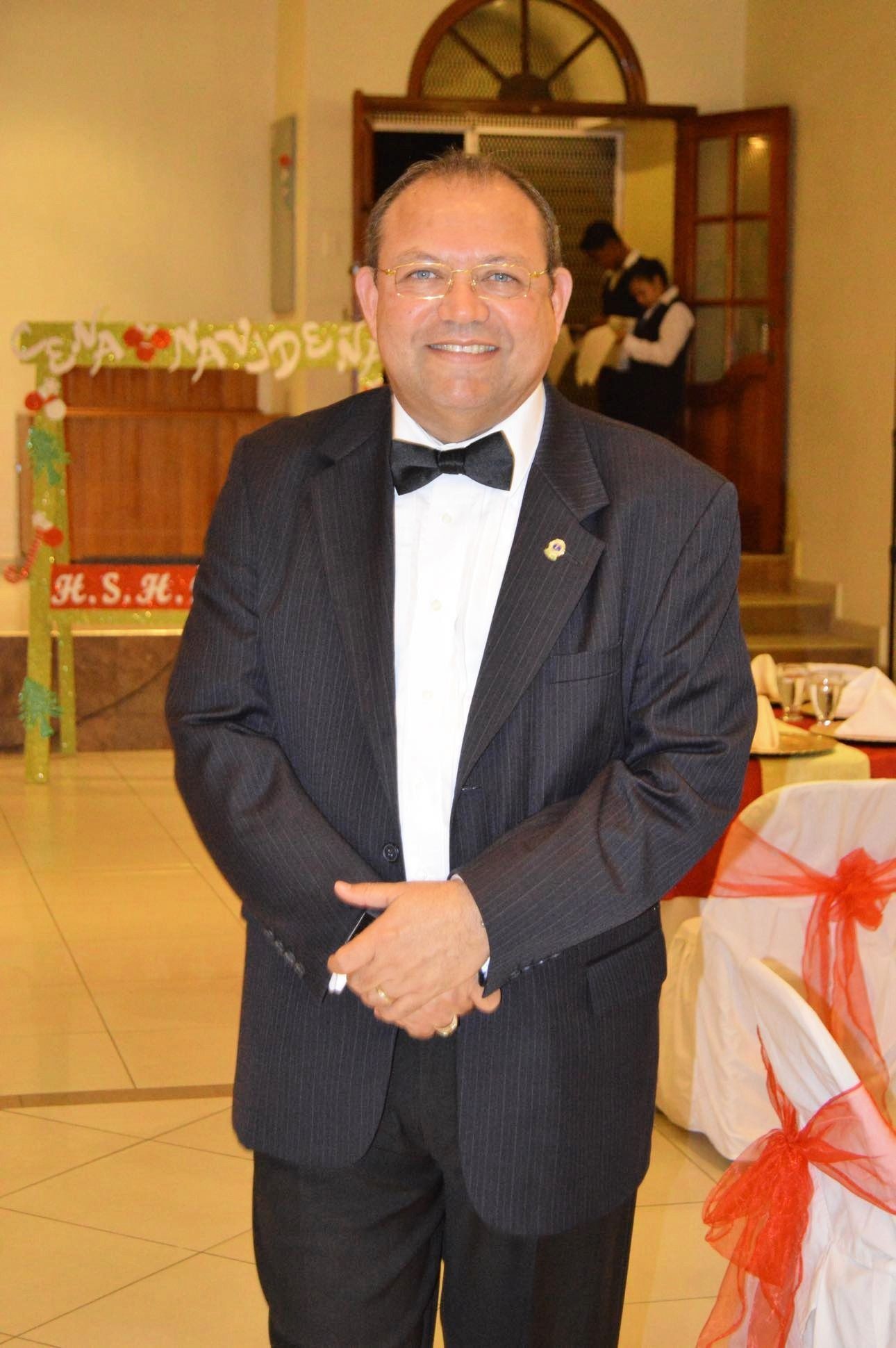 A man in a tuxedo is standing in front of a sign that says r.s.r.