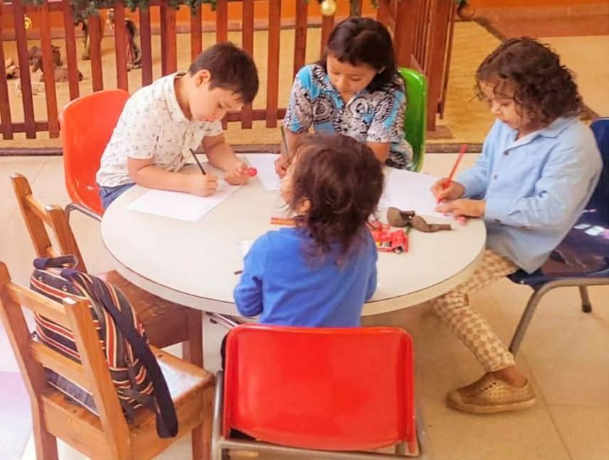 Newborn baby sleeping on a hospital bed, wearing a pink shirt, a knit hat, and mittens.