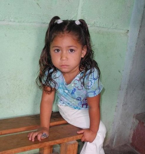 A little girl is sitting on a wooden bench