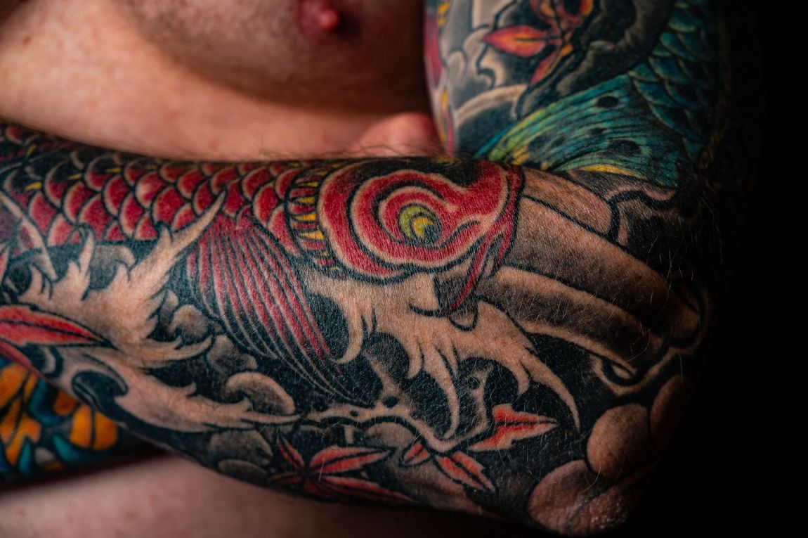A close up of a man 's arm with a lot of tattoos on it.