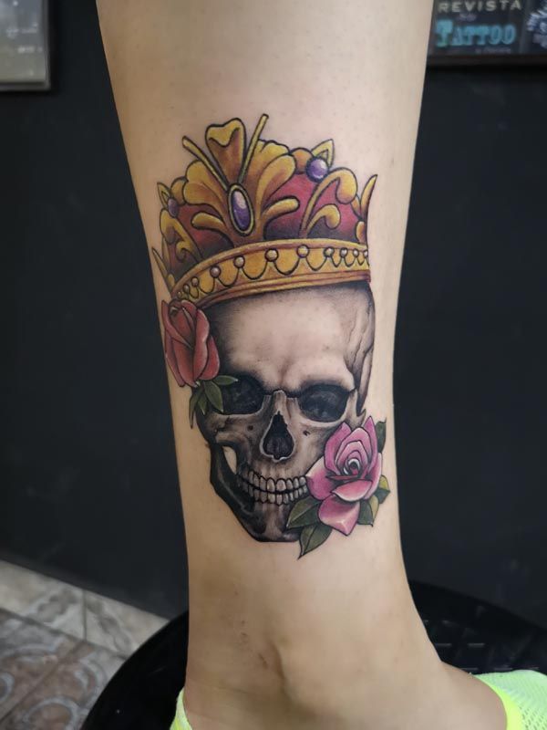 A tattoo of a skull with a crown and roses