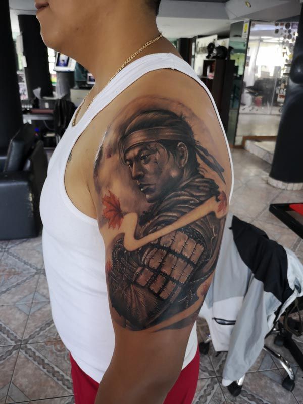 A man has a tattoo of a samurai on his arm