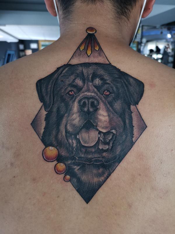A man has a tattoo of a dog on his back