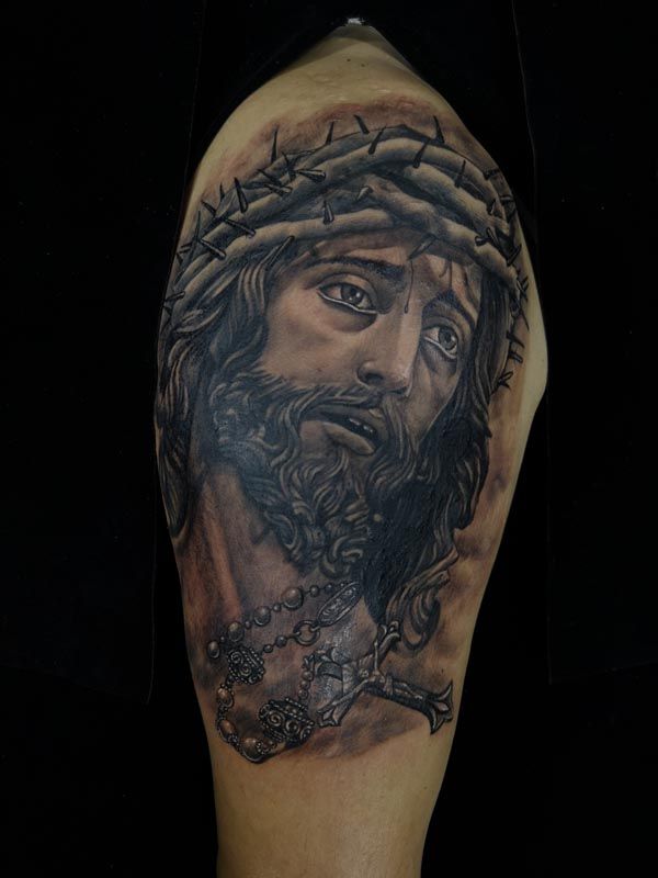 A black and white tattoo of jesus with a crown of thorns on his head.