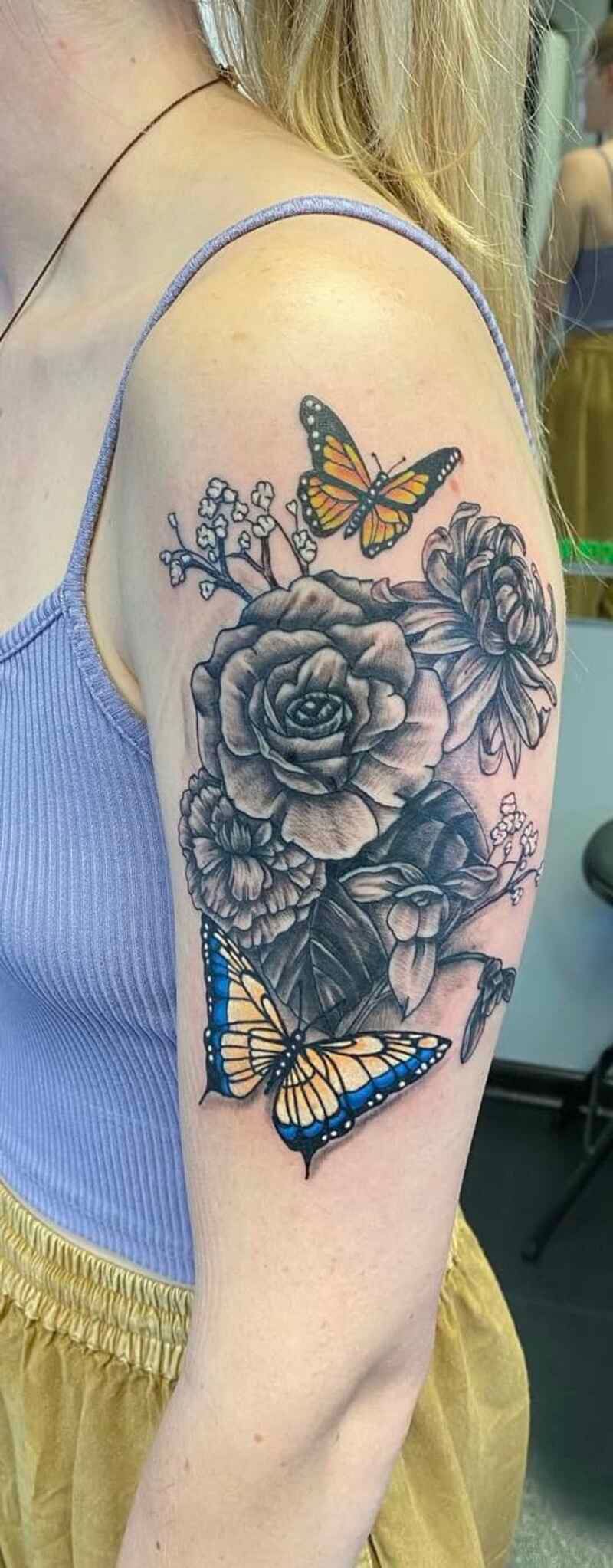 A woman has a tattoo of a rose and butterflies on her arm.