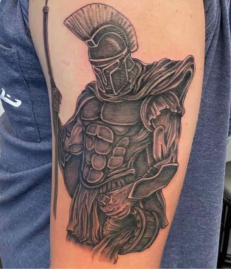 A man has a tattoo of a spartan warrior on his arm.