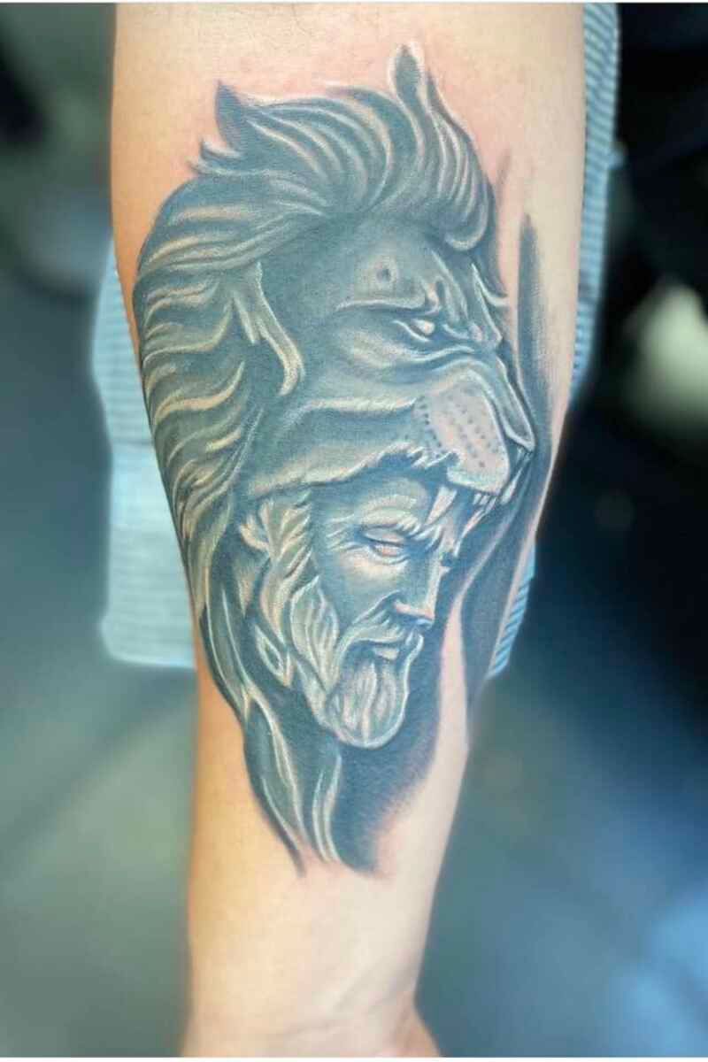 A person has a tattoo of a lion and a man on their arm.