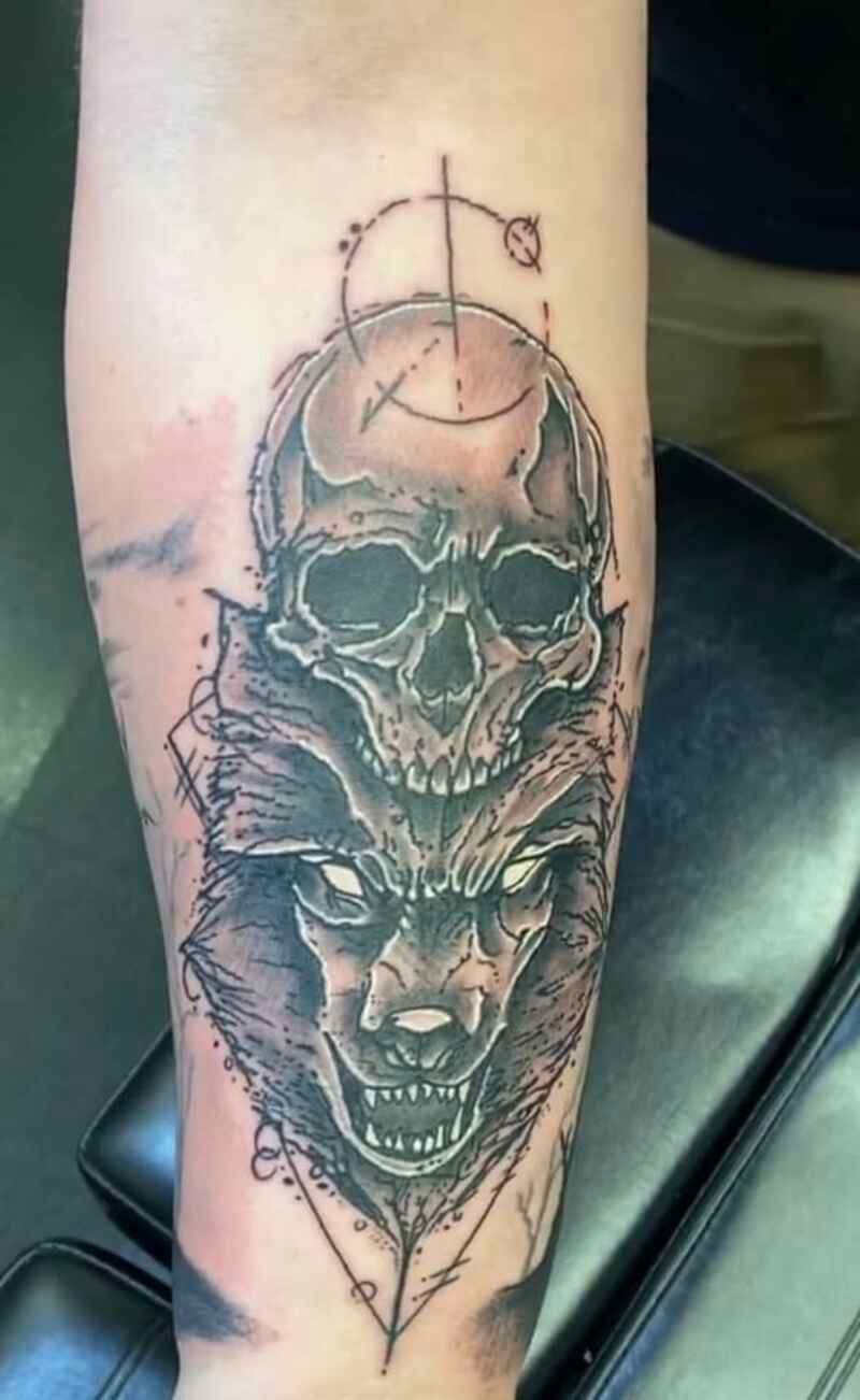A tattoo of a wolf and a skull on a person 's arm.