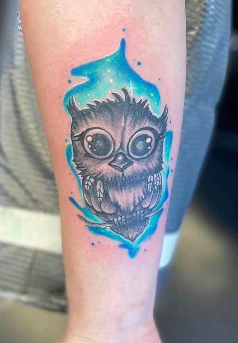 A person has a tattoo of an owl on their forearm.