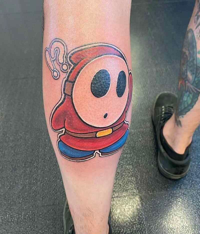 A person has a tattoo of shy guy on their leg.