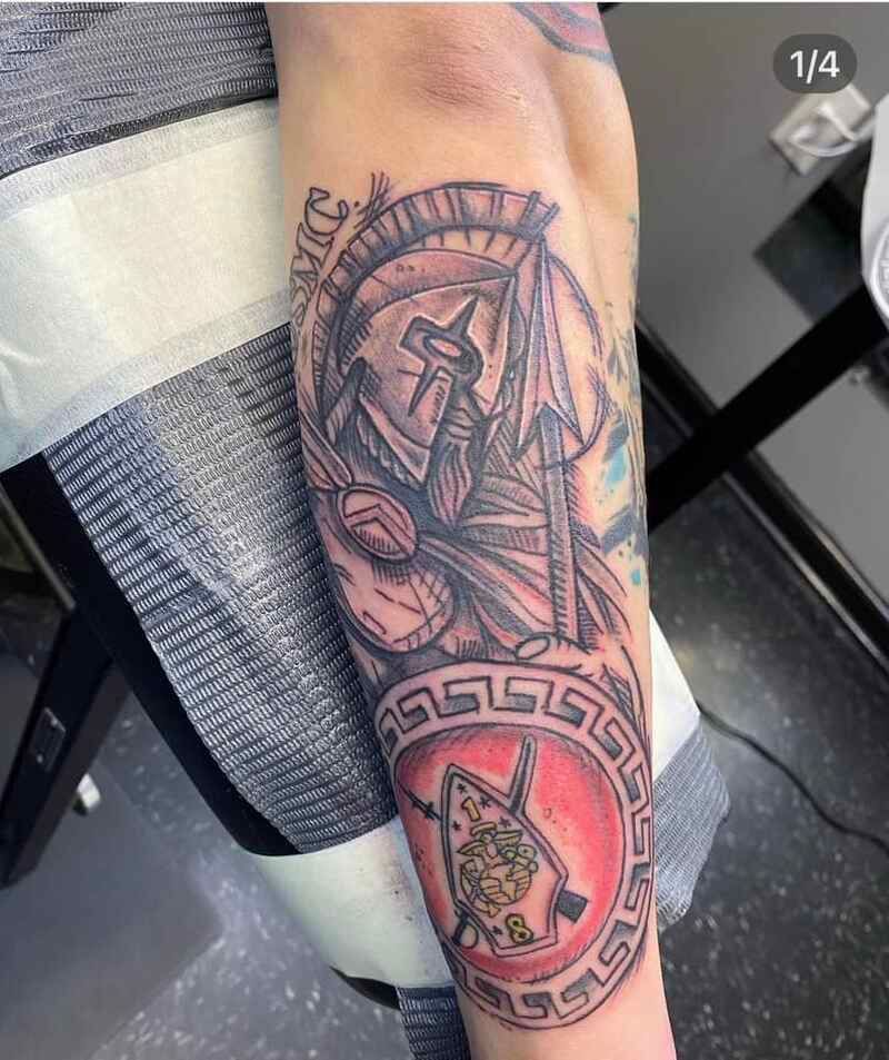 A person has a tattoo of a spartan warrior on their forearm.