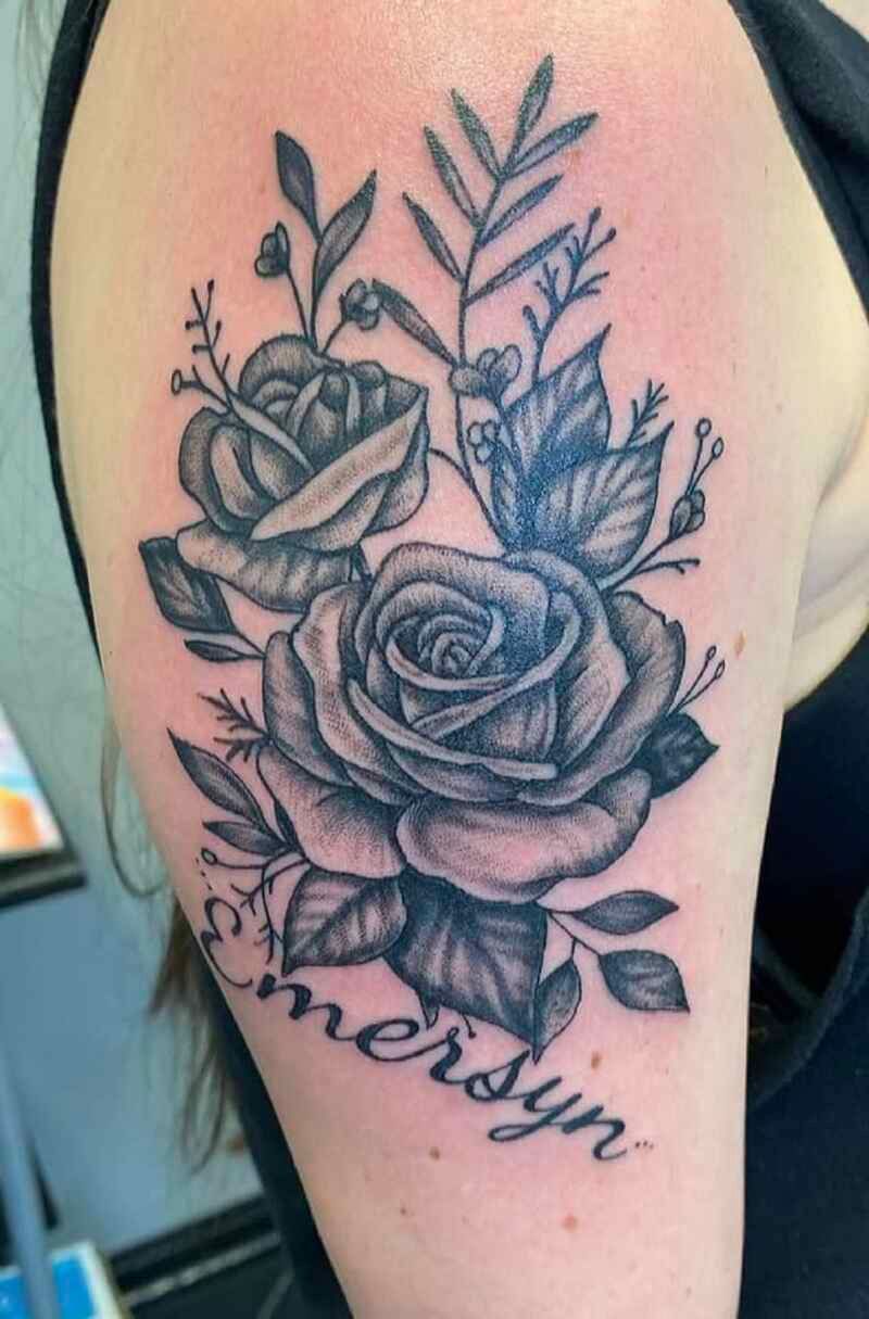 A woman has a tattoo of roses and leaves on her arm.
