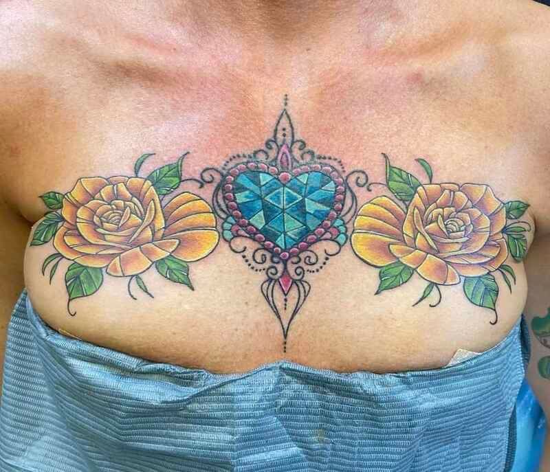 A woman has a tattoo of roses and a heart on her chest.