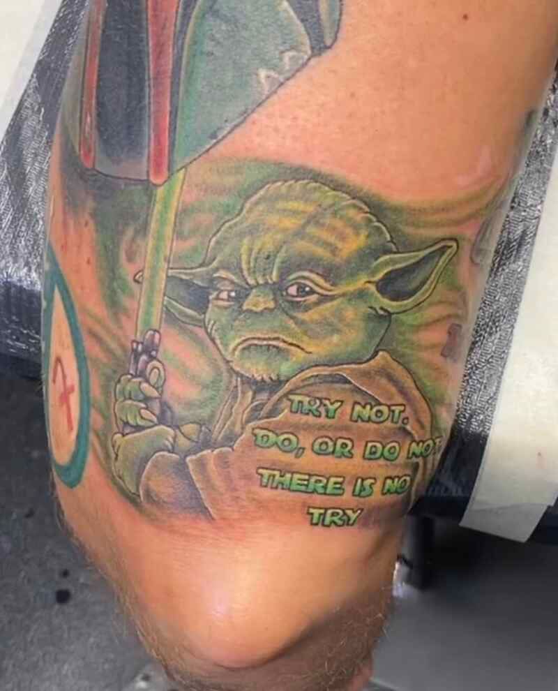A man has a tattoo of yoda on his leg.