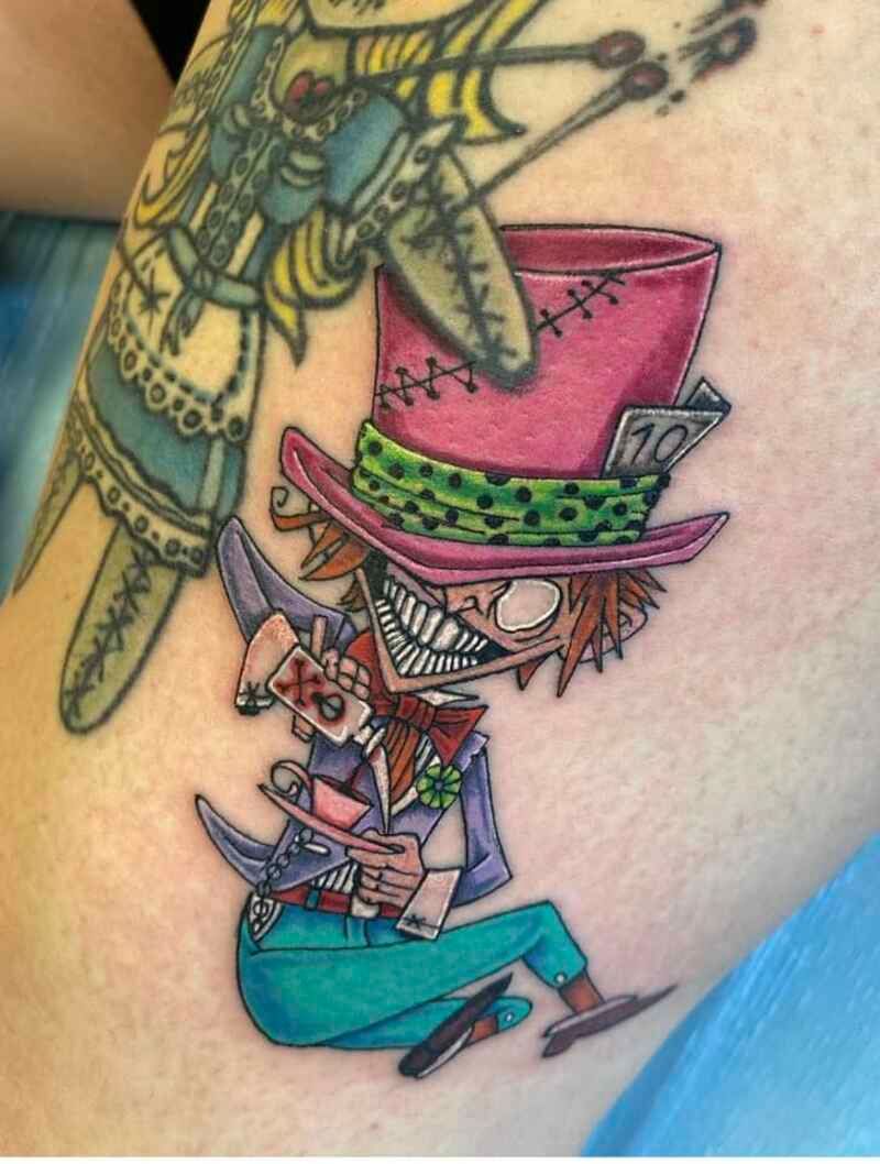 A person has a tattoo of a mad hatter on their arm.