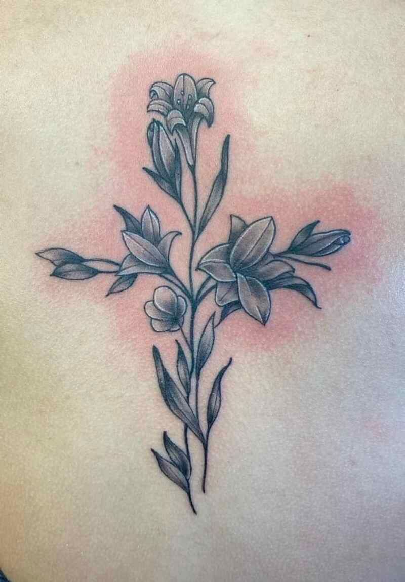 A tattoo of flowers in the shape of a cross on a person 's back