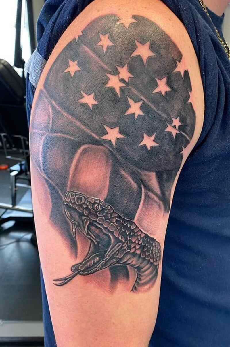 A man has a tattoo of an american flag and a frog on his arm