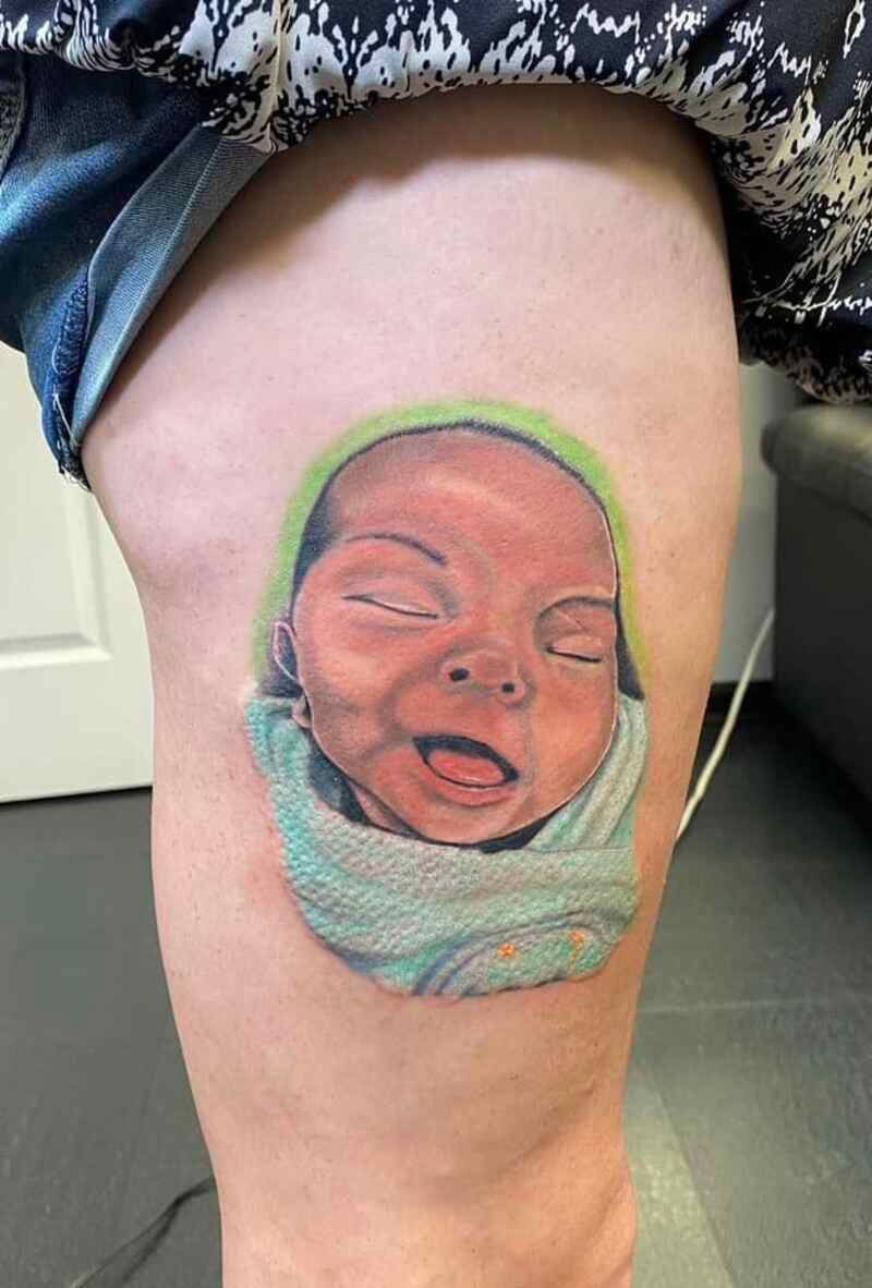 A woman has a tattoo of a baby on her leg.