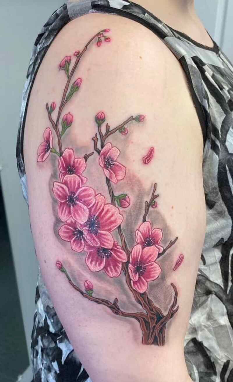 A woman has a tattoo of a cherry blossom tree on her arm.