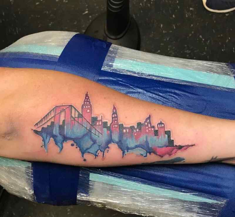 A person has a tattoo of a city skyline on their forearm
