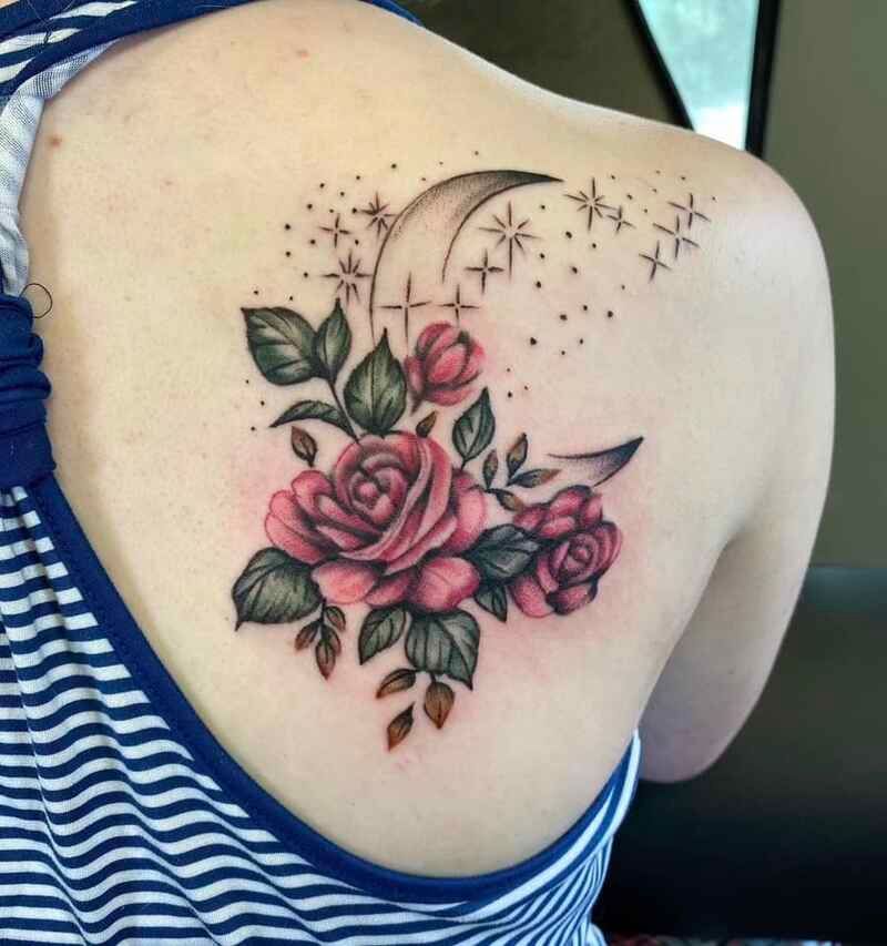 A woman has a tattoo of roses and a crescent moon on her back