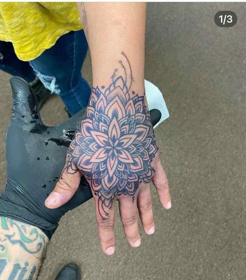 A person is getting a tattoo on their hand.