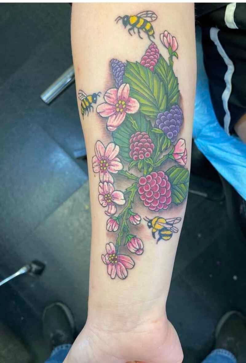 A tattoo of flowers and bees on a person 's arm