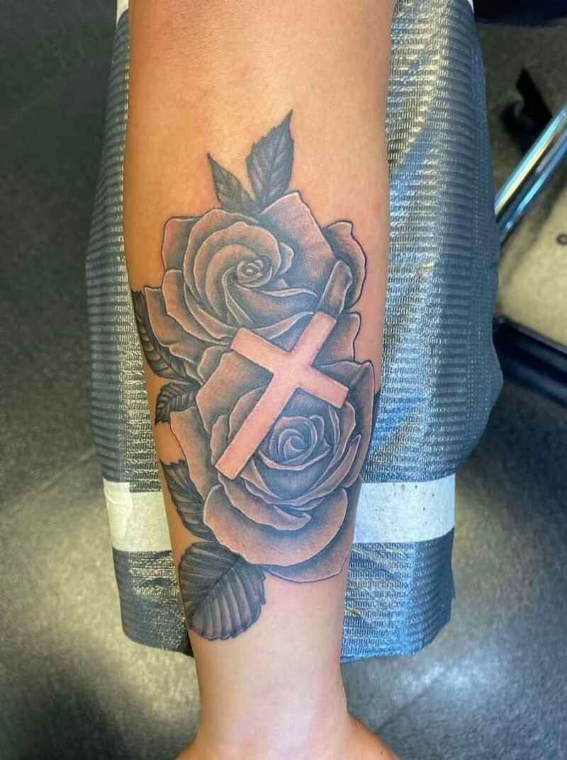 A cross on top of flowers tattoo