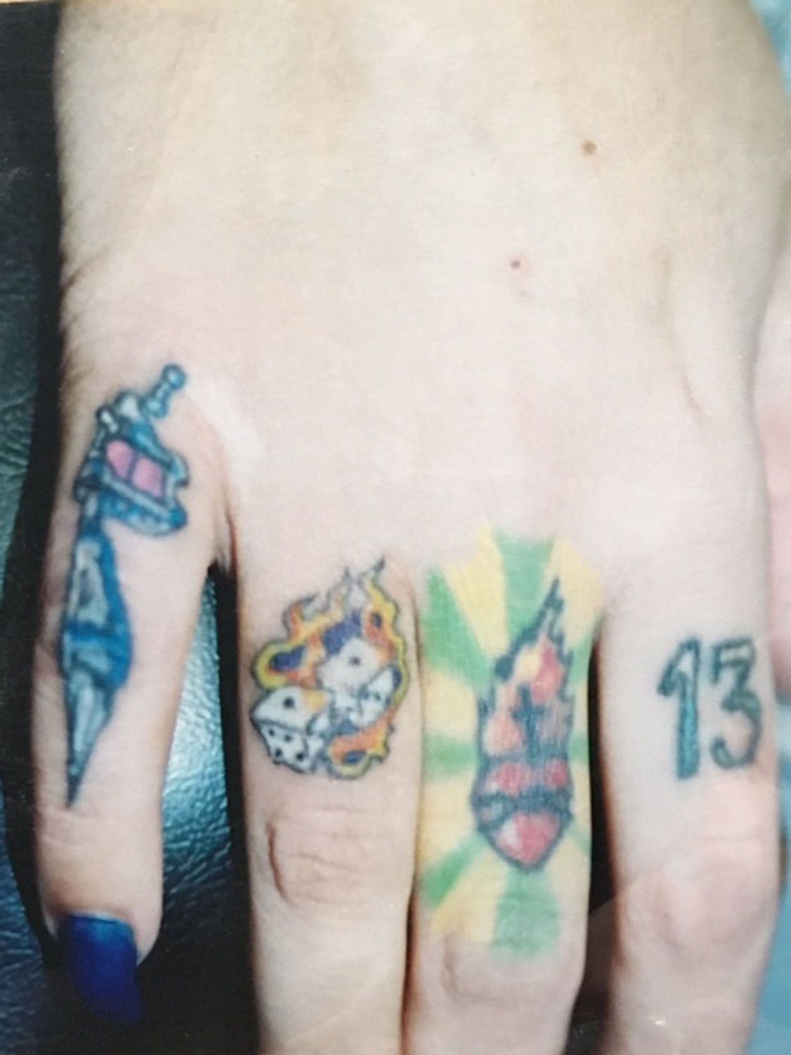 A close up of a person 's hand with three tattoos on it including the number 13