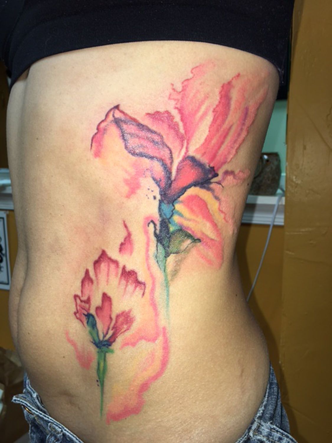 A woman has a tattoo of flowers on her side